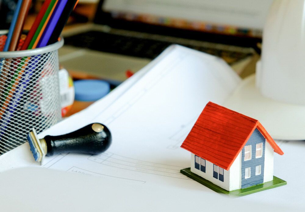 A Small Model House is Sitting on Top of a Piece of Paper Next to a Stamp — Key2 Conveyancing In Diamond Beach, NSW