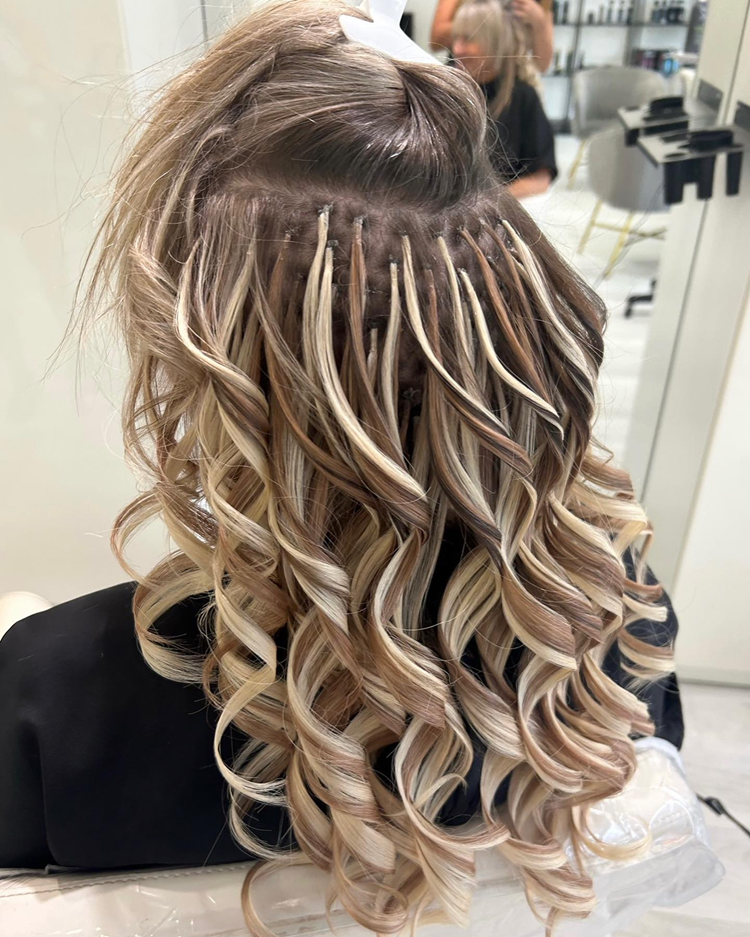 A woman with curly hair is getting her hair done in a salon.