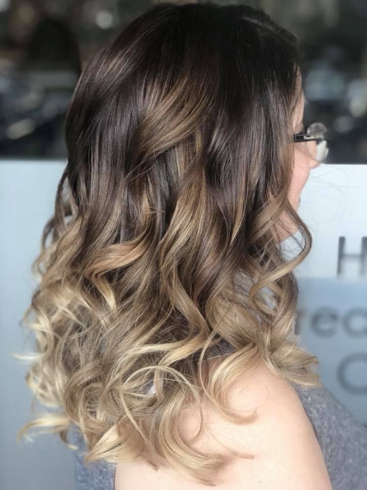 A woman with long curly hair is wearing glasses.