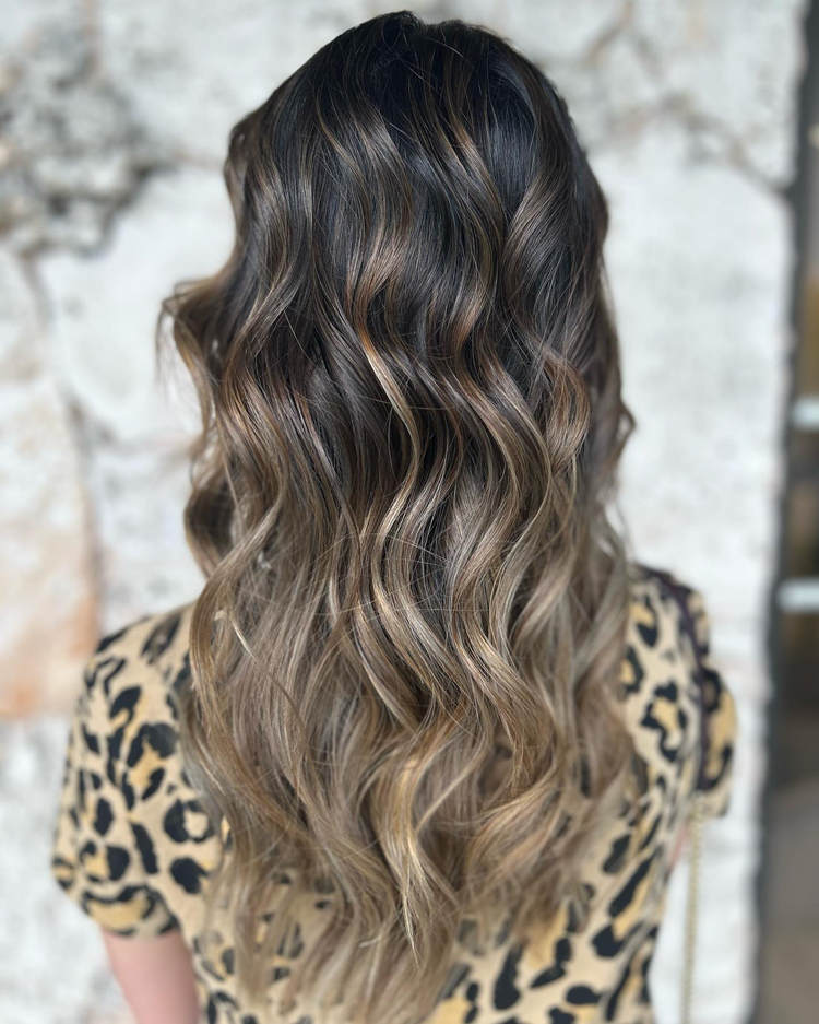 A woman with long wavy hair is wearing a leopard print shirt.