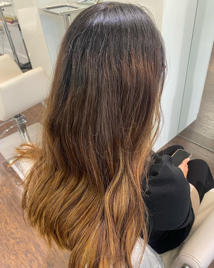 A woman with long hair is sitting in a chair in a salon.