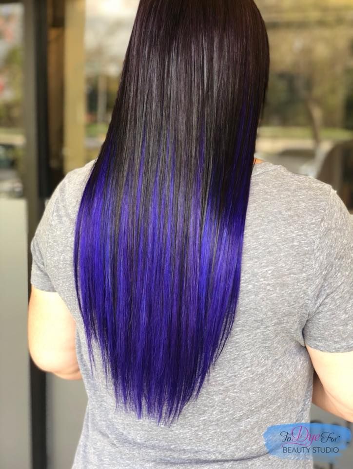 A woman with long black hair and purple highlights is wearing a gray shirt.