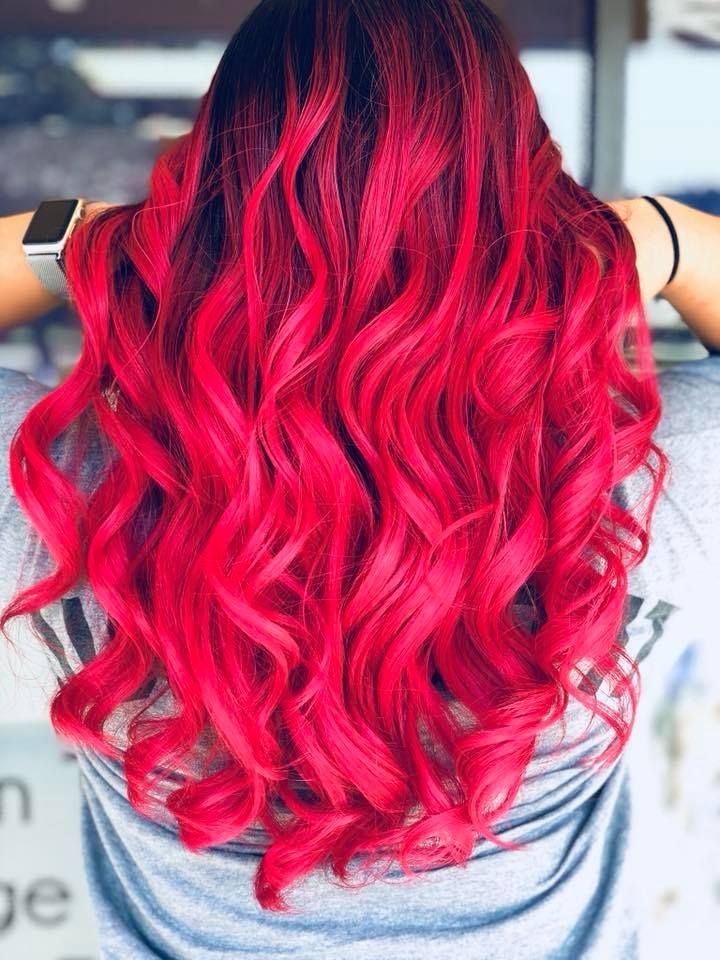 A woman with long red hair is wearing a gray shirt.