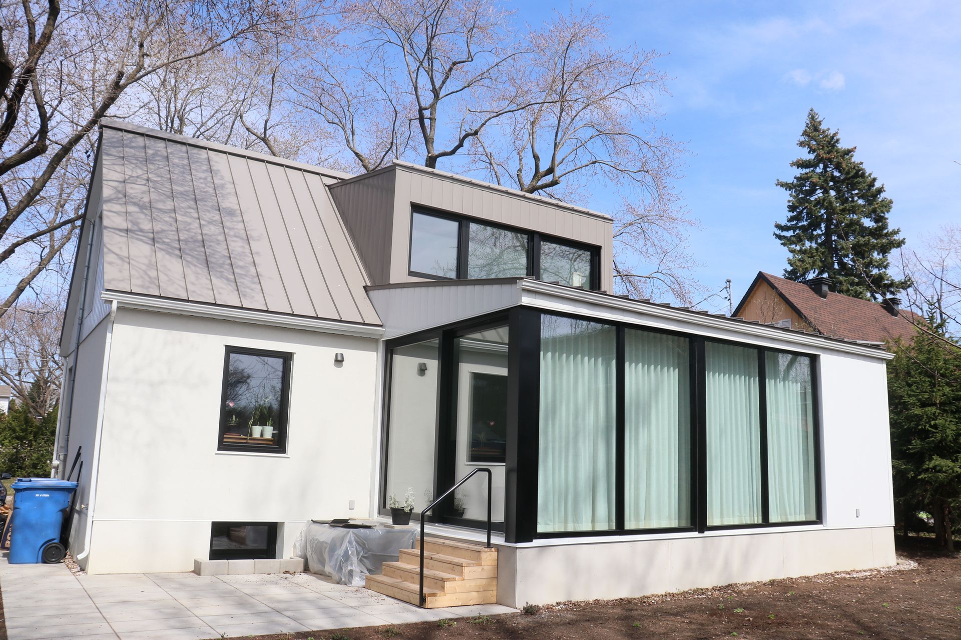Une maison blanche avec un toit gris et beaucoup de fenêtres.