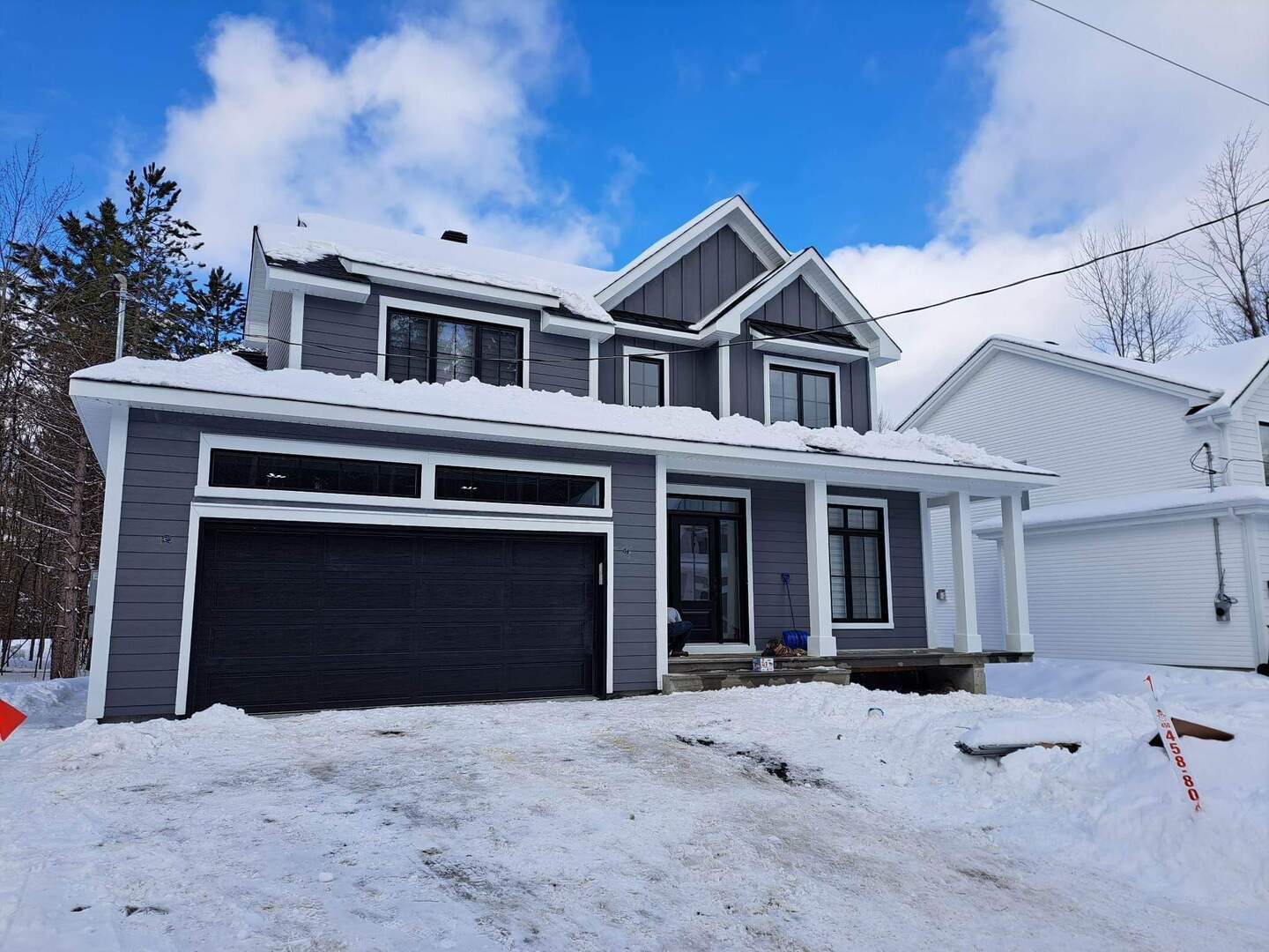 Une grande maison avec un garage est recouverte de neige.