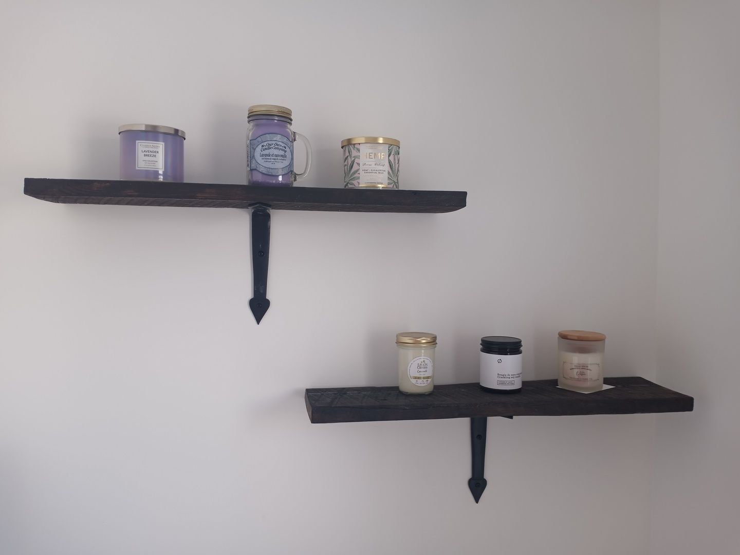 Deux étagères remplies de pots et de bougies sur un mur blanc