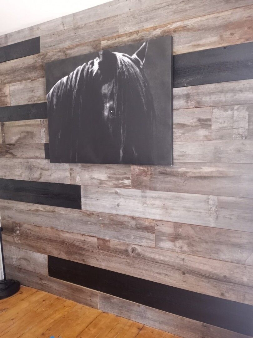 Un tableau représentant un cheval est accroché sur un mur en bois.