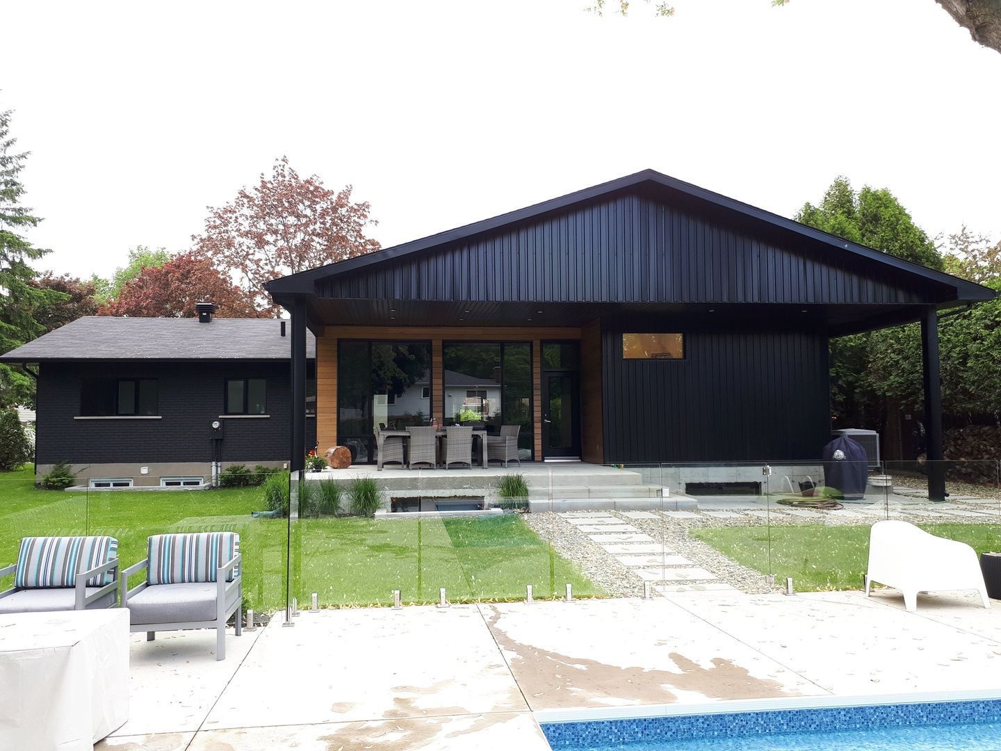 Une maison noire avec une piscine devant