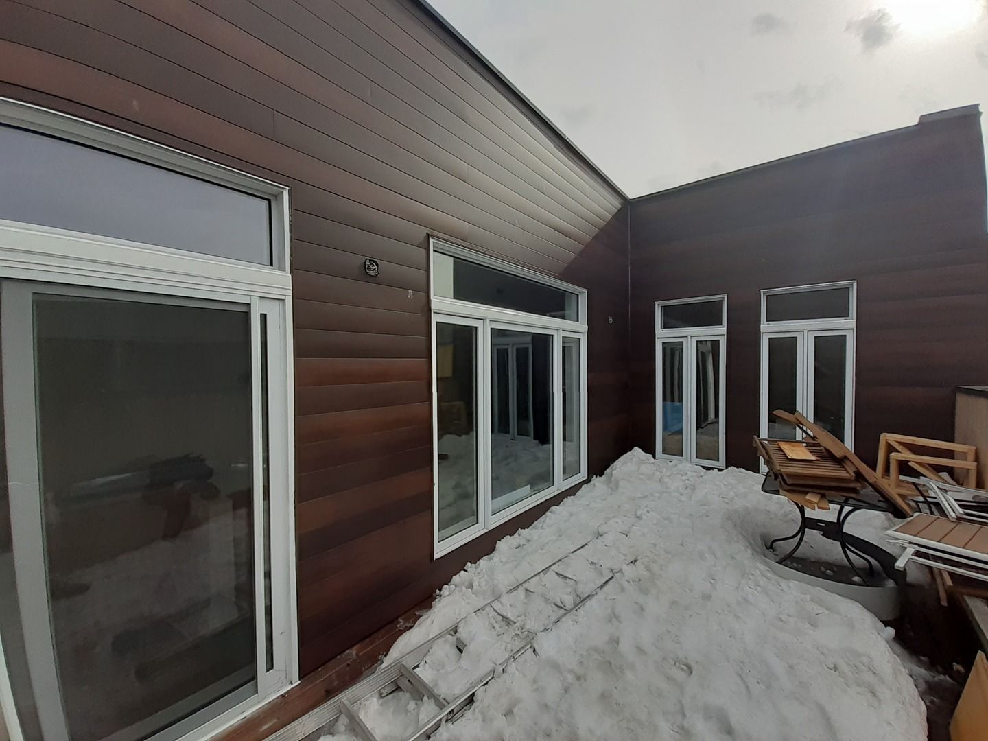 Une maison avec beaucoup de fenêtres et de la neige sur le sol