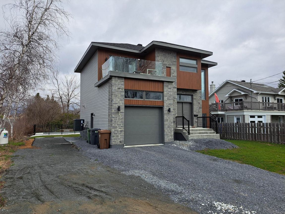 Une grande maison avec un garage et une allée devant.