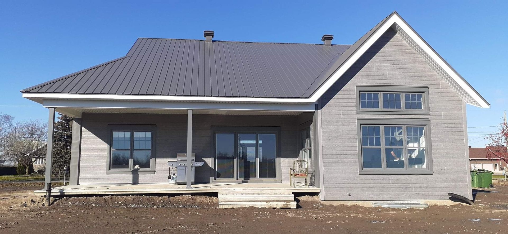 Une petite maison avec un porche et un toit gris