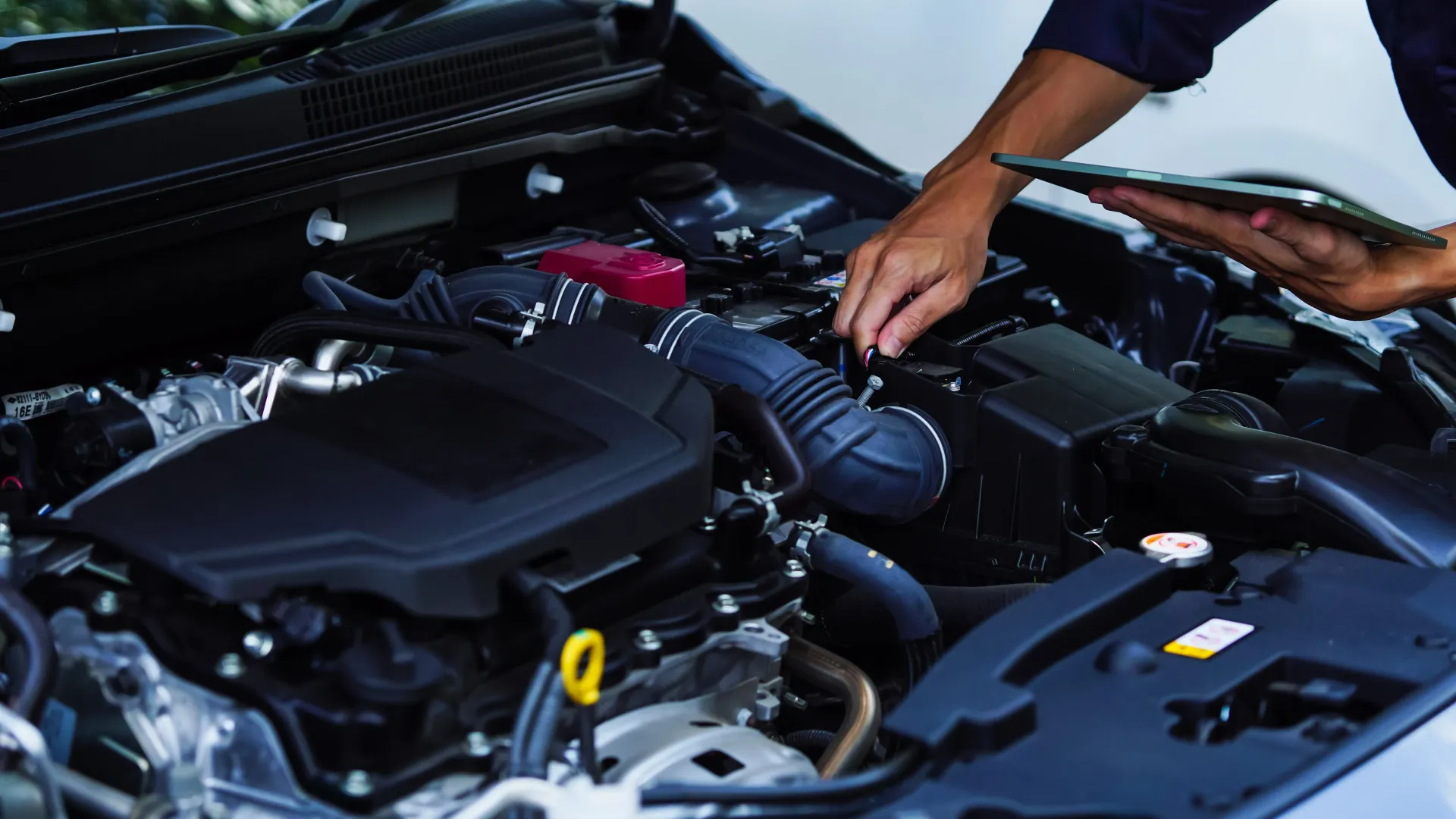 Mechanic inspecting car engine with tablet | 1st Choice Autoworks