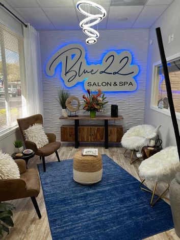 Blue 22 Salon & Spa waiting area with blue rug, chandelier, chairs, and decor signage