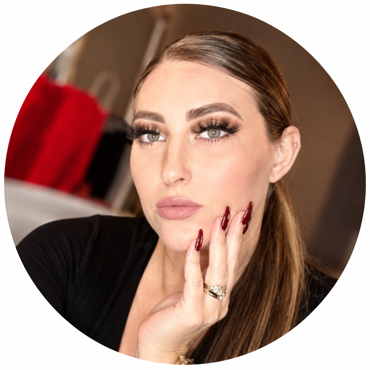 Blue 22 Salon & Spa Close-up portrait of a woman with long hair, makeup, and burgundy nails, resting her chin on her hand