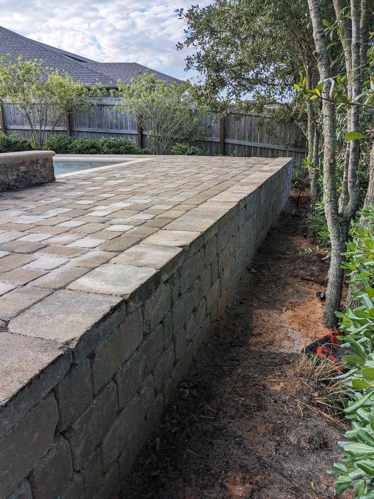 Stone patio with retaining wall beside trees and landscaped garden area