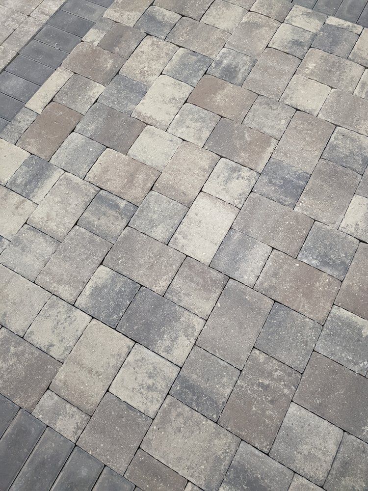Gray and tan interlocking pavers arranged in a diagonal pattern on a paved surface