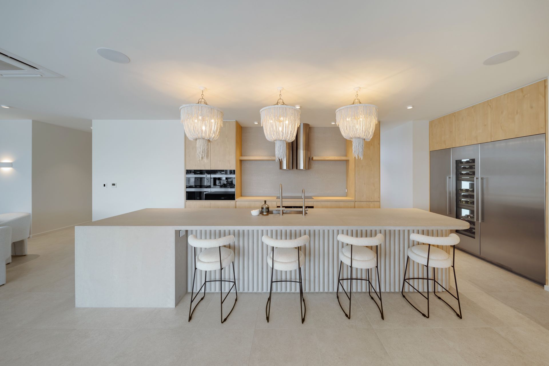 Modern Kitchen With White Island, Four Bar Stools, Three Chandeliers, And Stainless Steel Appliances — Simon Bell Constructions in Alice River, QLD