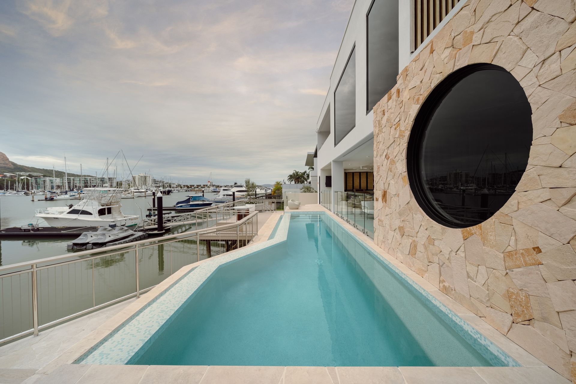 A Rooftop Pool Overlooking A Marina With Boats. Building With A Round Window And Beige Stone — Simon Bell Constructions in Alice River, QLD