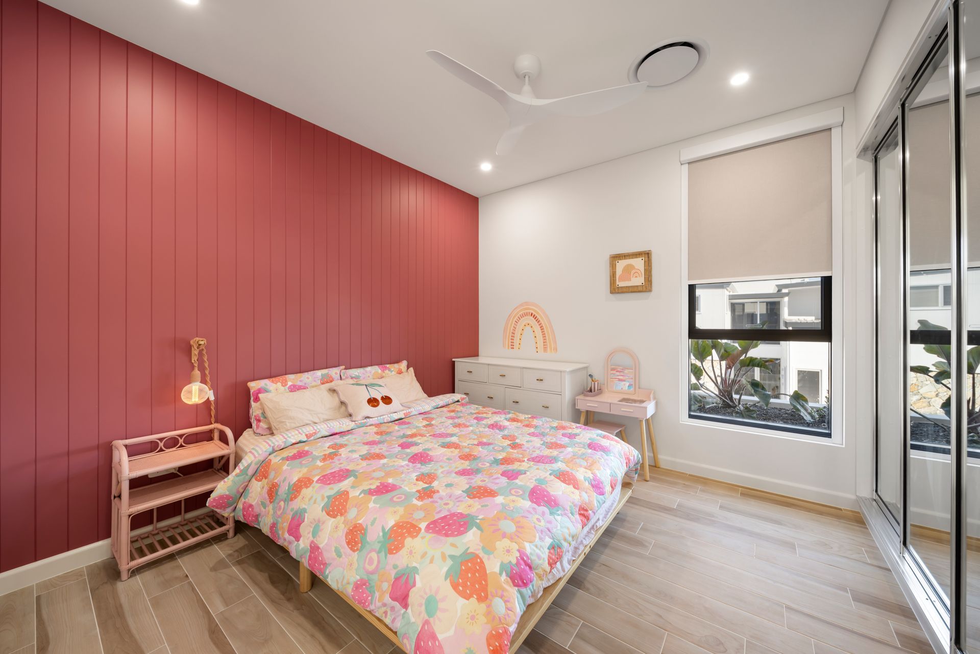 Bright Bedroom With Red Accent Wall, Floral Bedspread — Simon Bell Constructions in Alice River, QLD