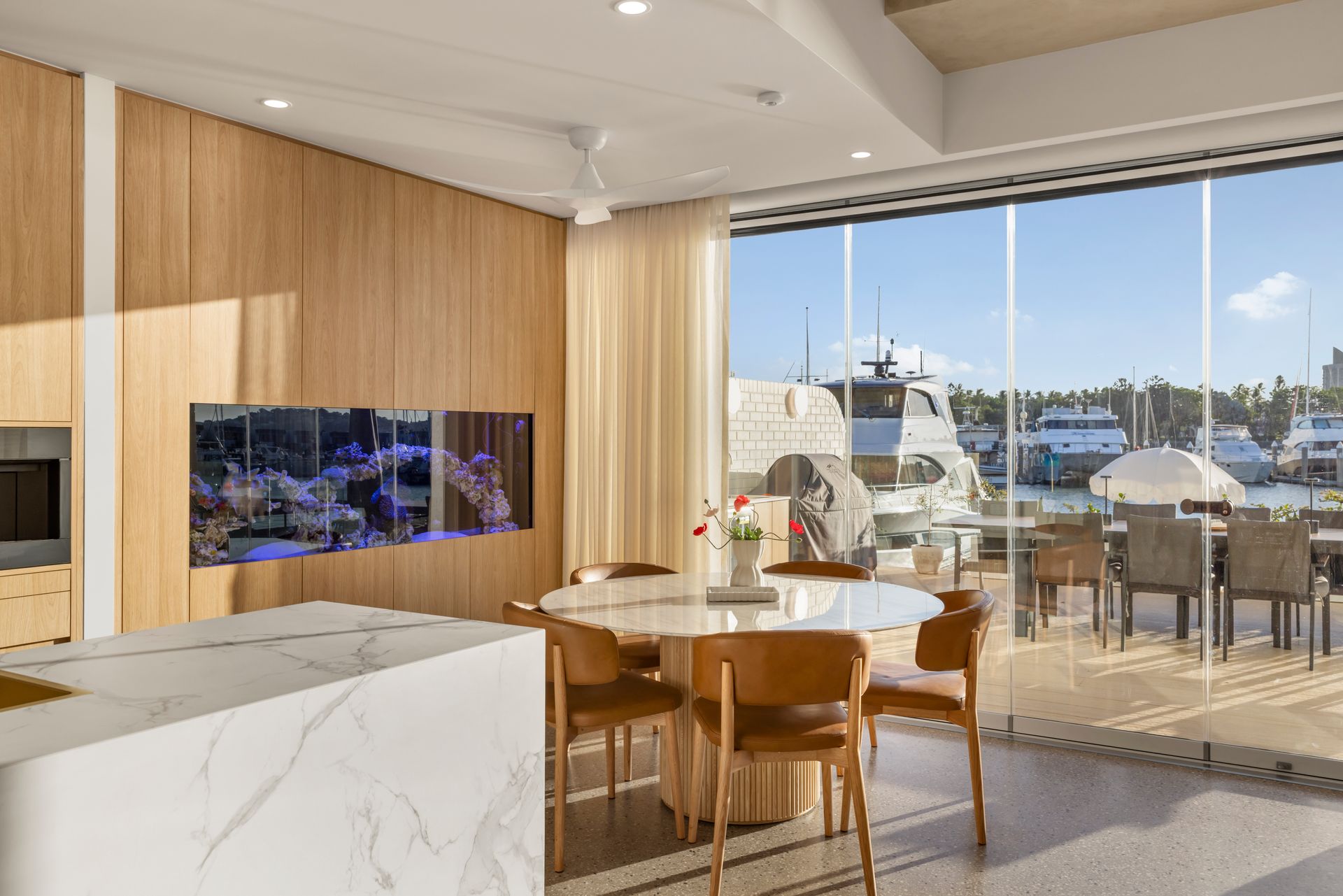Modern Kitchen and Dining Area Overlooking a Sunny Waterfront Patio and Marina — Simon Bell Constructions in Alice River, QLD