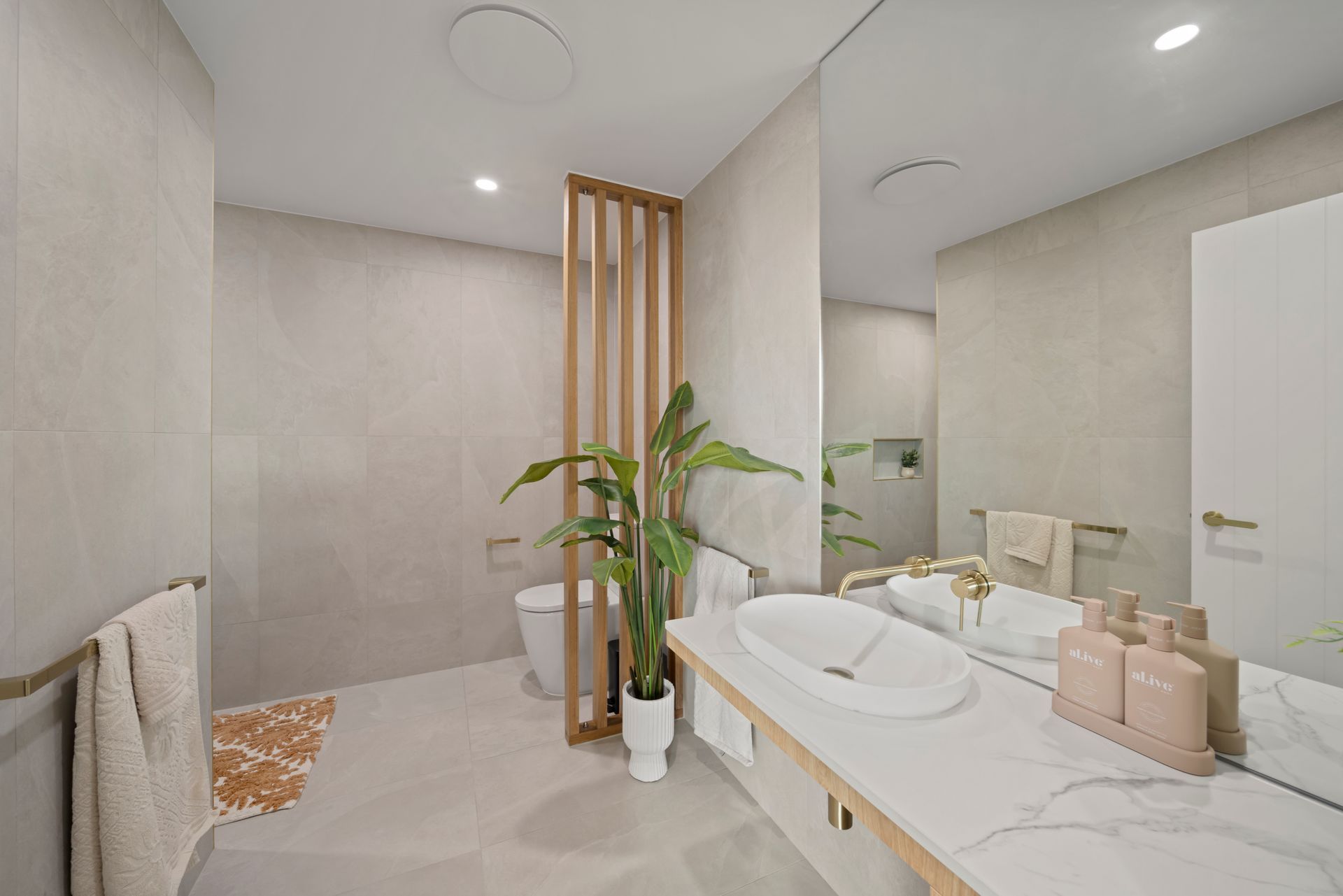 Modern Beige Bathroom With a Marble Vanity, Round Mirror — Simon Bell Constructions in Alice River, QLD