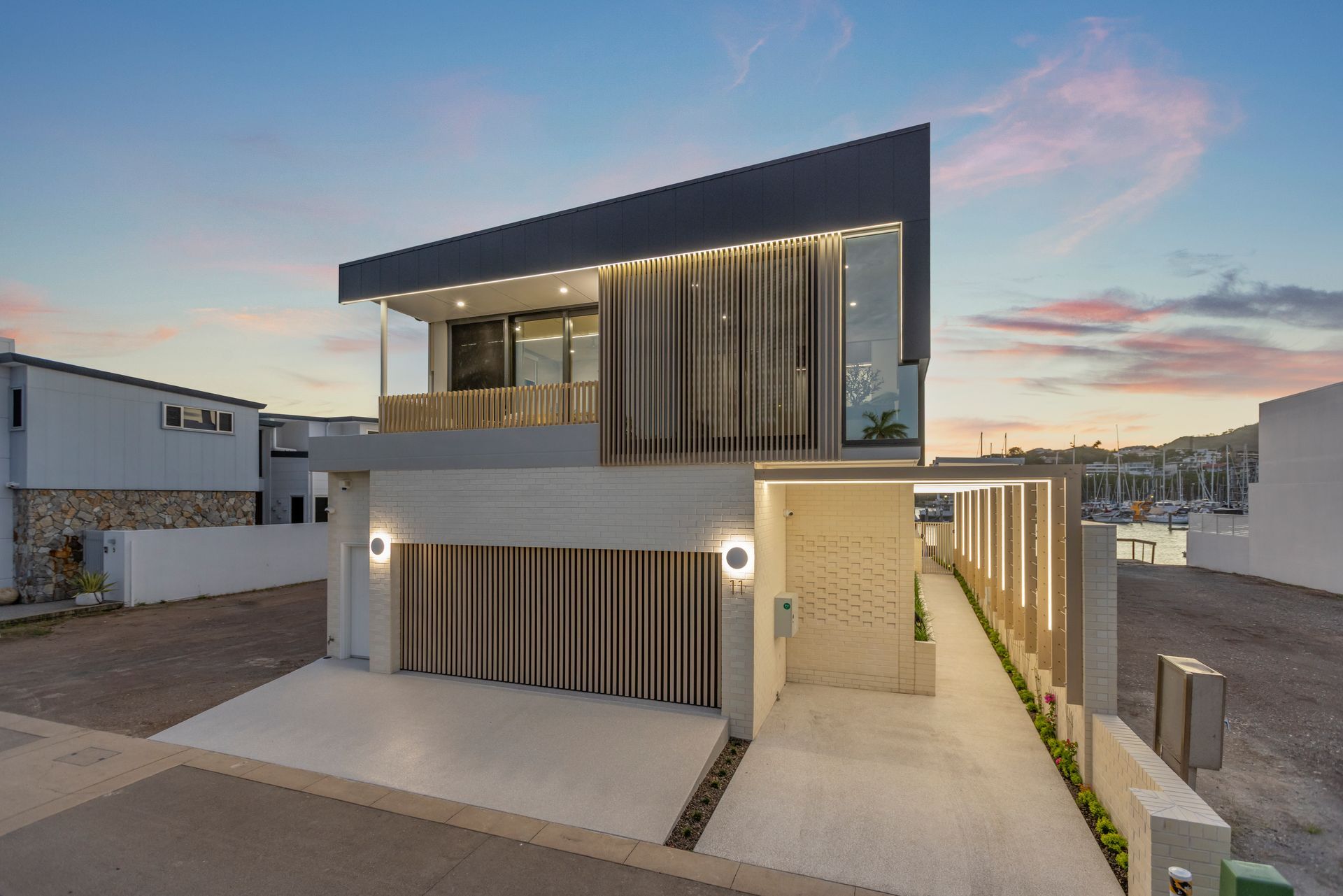 Modern Two-story House With Sleek Gray Exterior and Warm Accent Lighting at Dusk — Simon Bell Constructions in Alice River, QLD