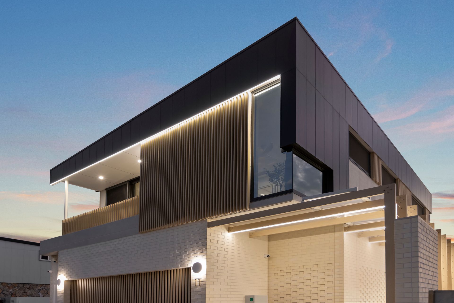 Modern Two-story House Exterior at Dusk With Dark Panels — Simon Bell Constructions in Alice River, QLD