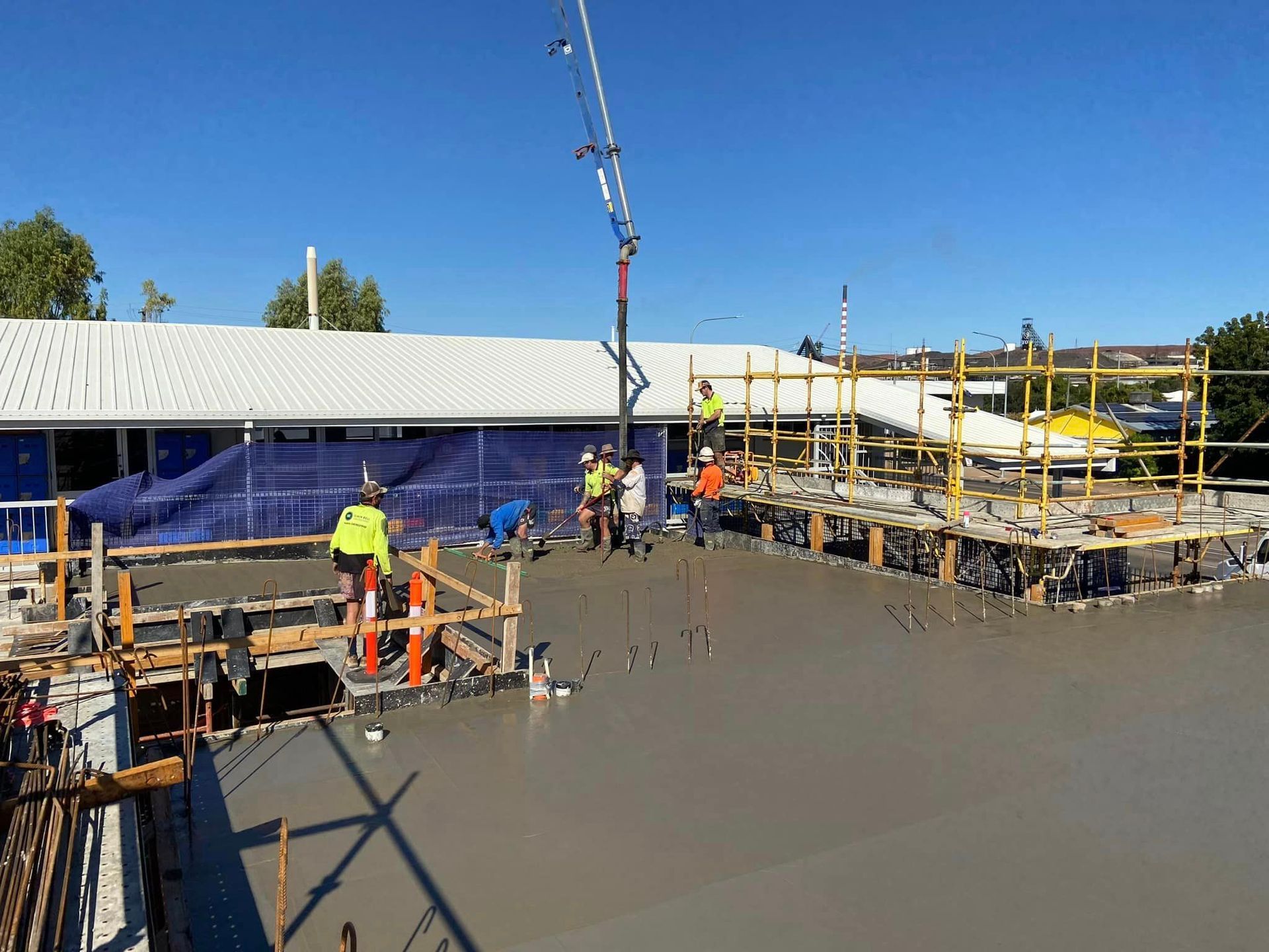 Construction Workers Pouring Concrete On A Roof With A Boom Pump, Sunny Day — Simon Bell Constructions in Alice River, QLD