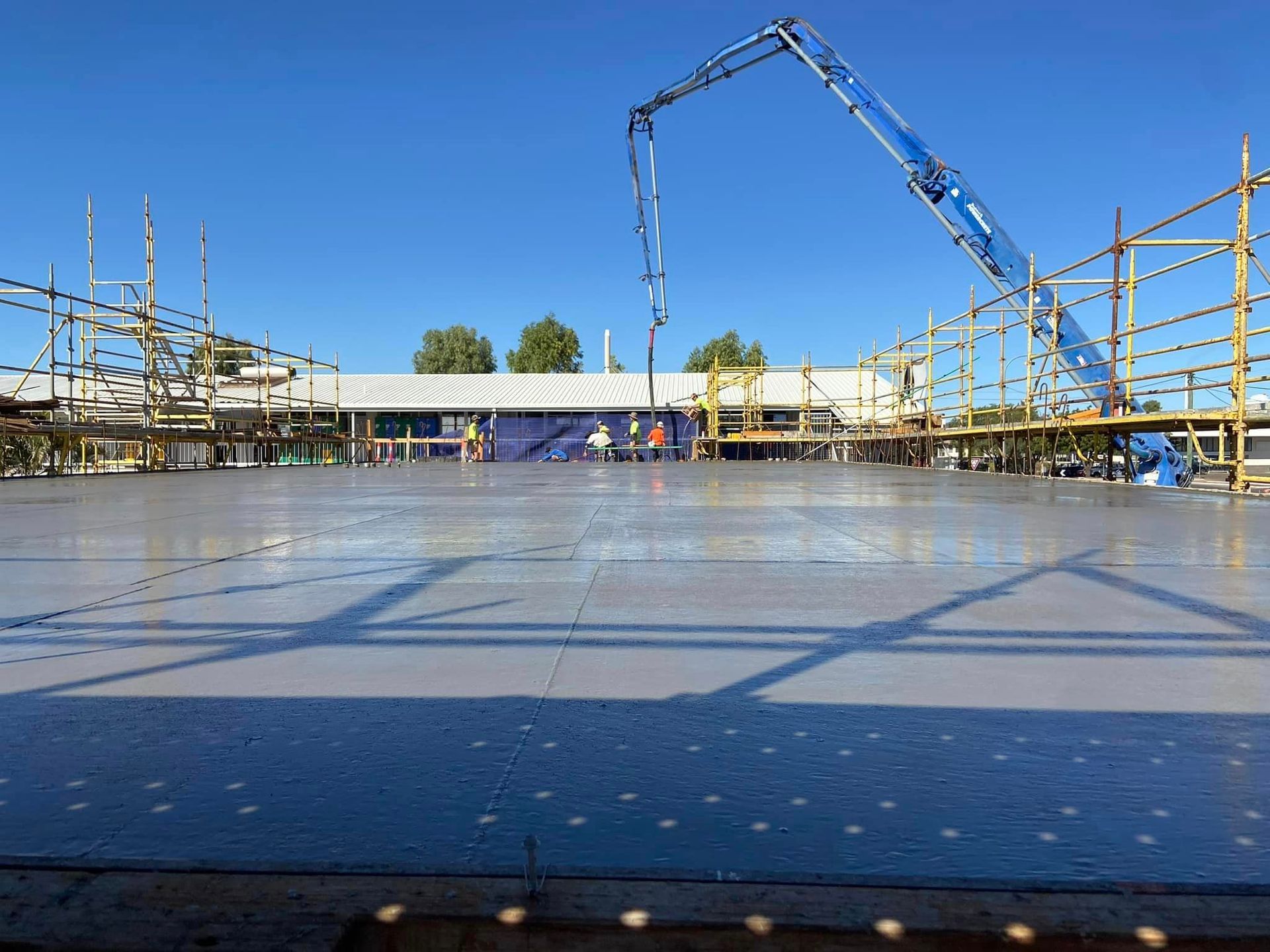 Freshly Poured Concrete Slab Being Smoothed, With Concrete Pump And Scaffolding In View — Simon Bell Constructions in Alice River, QLD