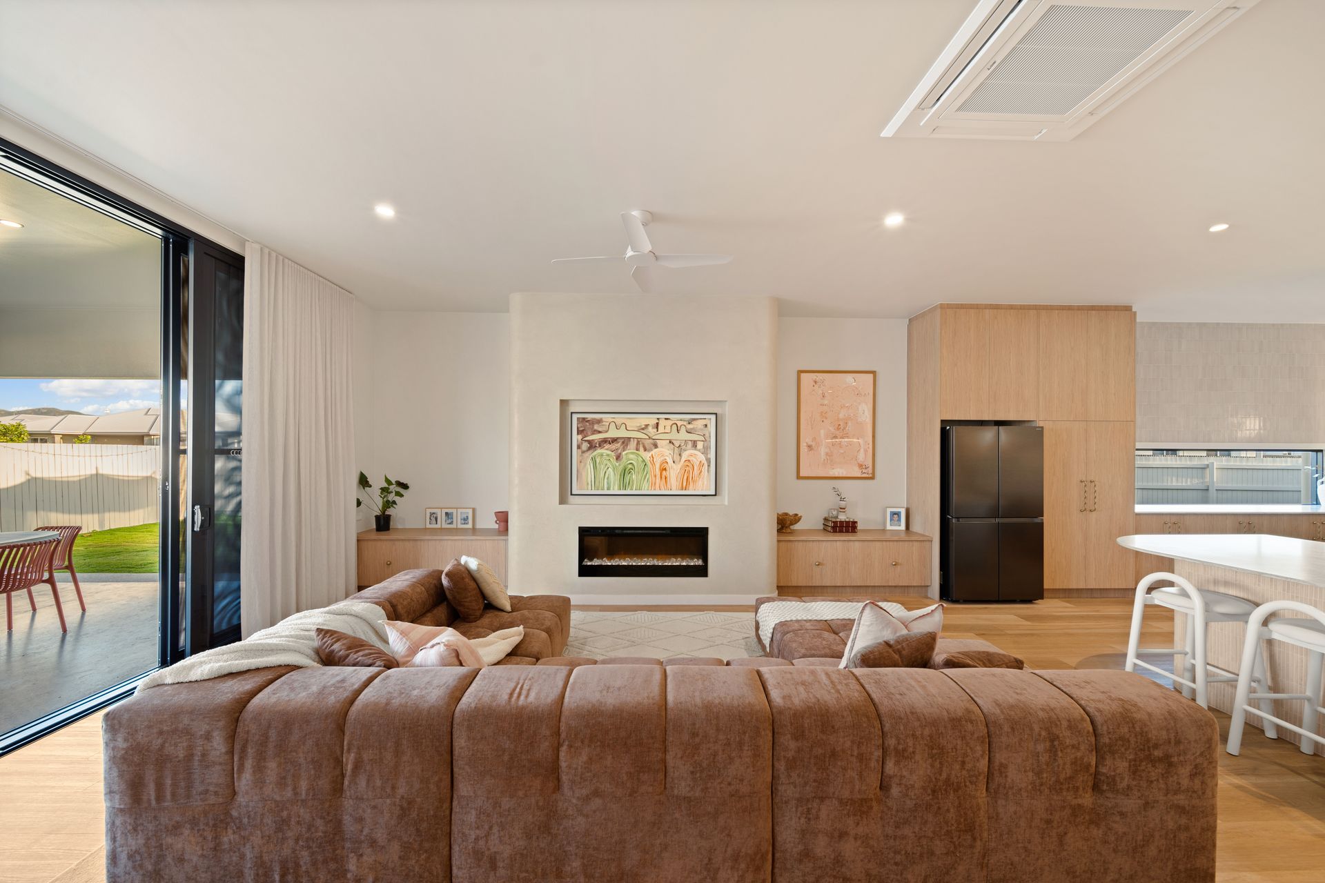 Modern Living Room With Brown Sectional, Fireplace, Wall Art — Simon Bell Constructions in Alice River, QLD