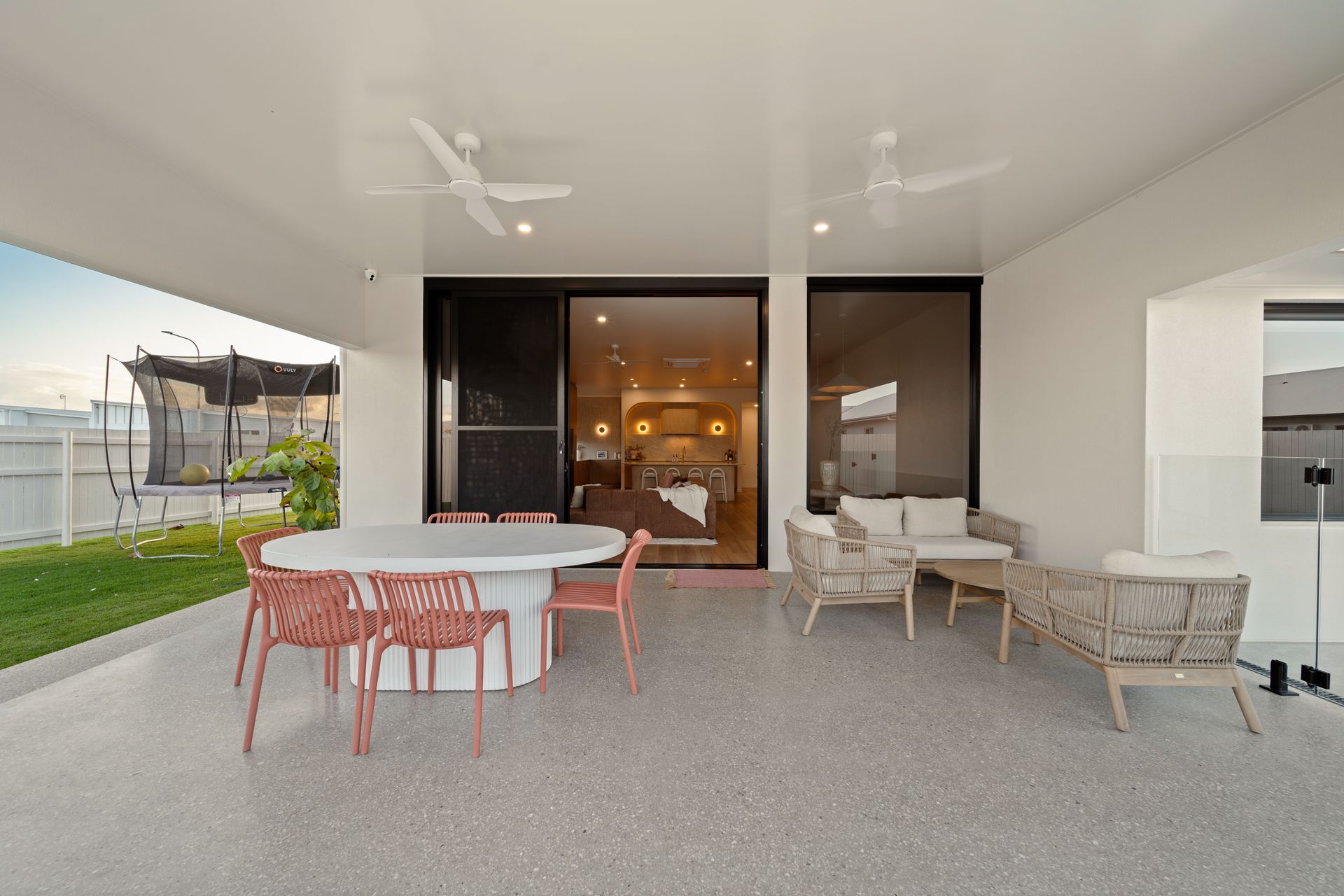 Covered Patio With White Table and Coral Chairs, Wicker Seating, and a Waterfront View — Simon Bell Constructions in Alice River, QLD