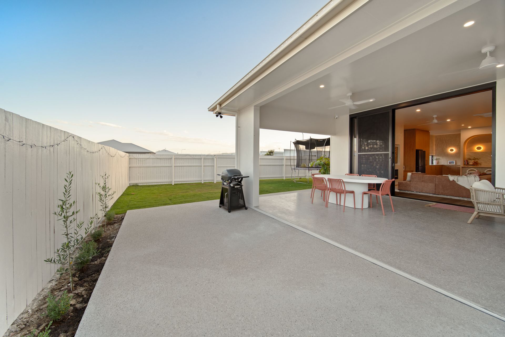 Covered Patio With Dining Table and Sofa Beside a Concrete Yard and White Fence — Simon Bell Constructions in Alice River, QLD