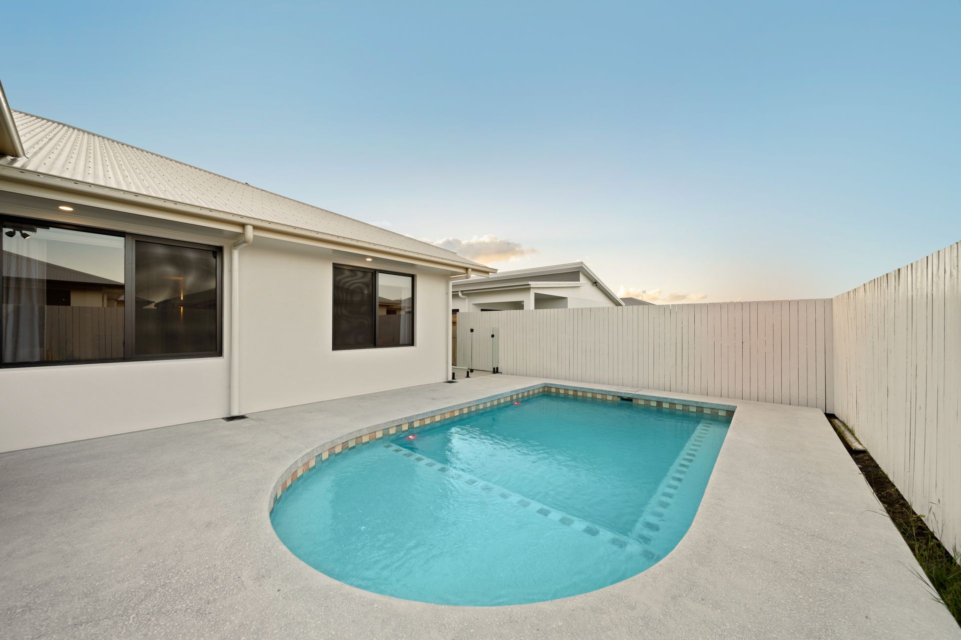 Modern Backyard With a Small Turquoise Pool Beside a White House and Privacy Fence — Simon Bell Constructions in Alice River, QLD