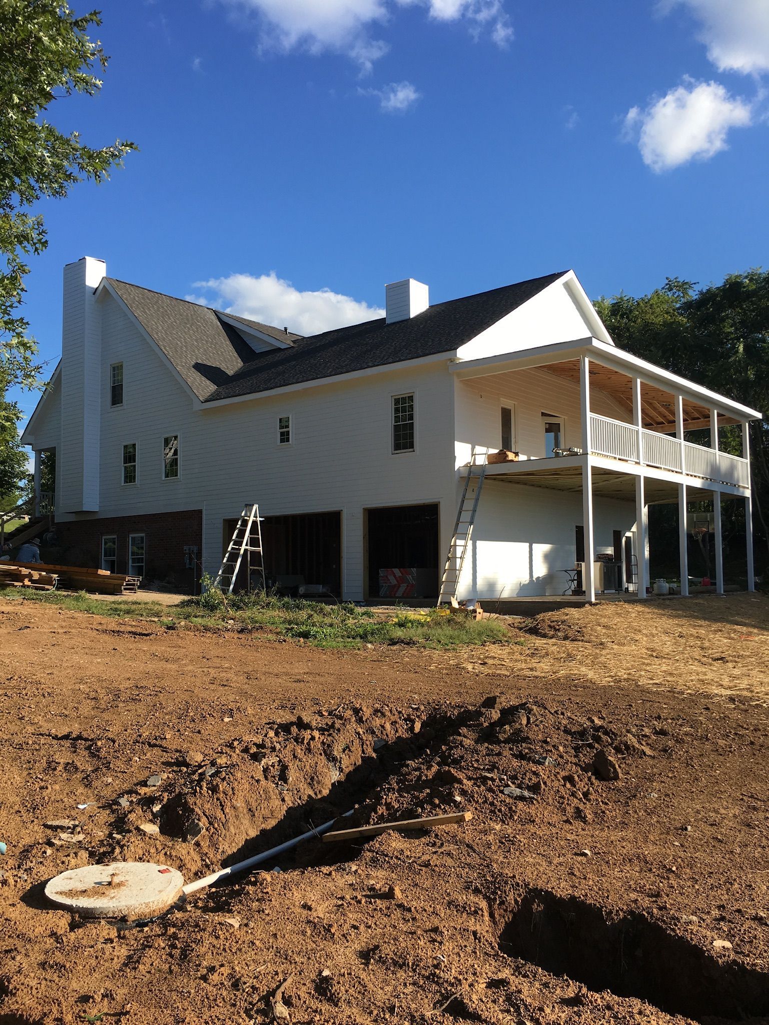 a large white house is sitting in the middle of a dirt field