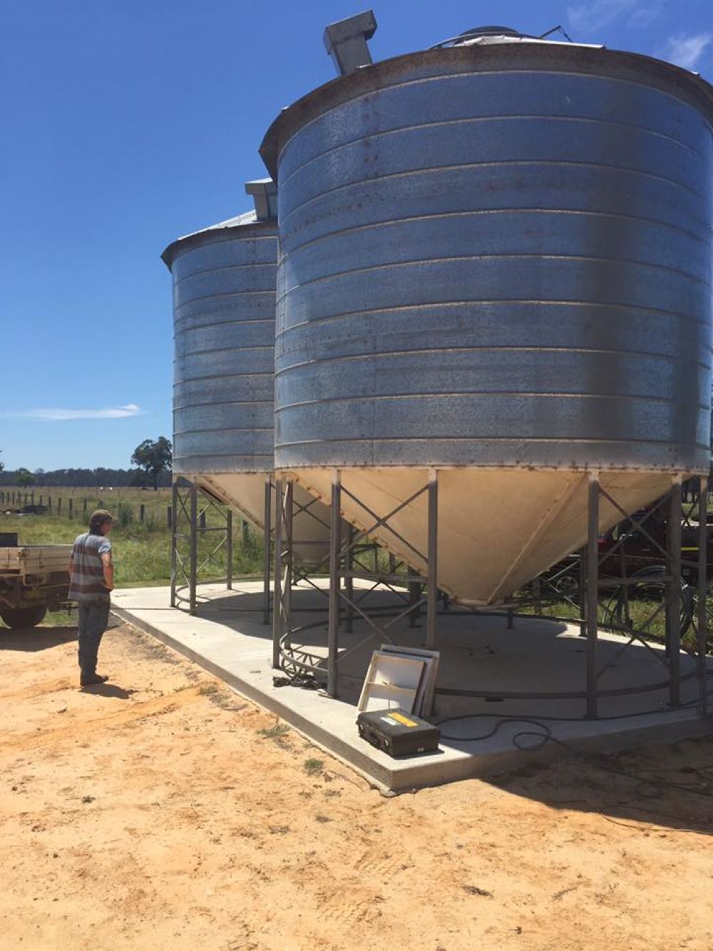 A Man is Standing in Front of a Row of Silos — Wallamore Grain & Produce In Barraba, NSW