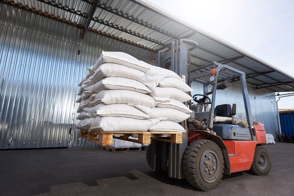 A Forklift is Carrying a Pallet of Bags in a Warehouse — Wallamore Grain & Produce In Gunnedah, NSW