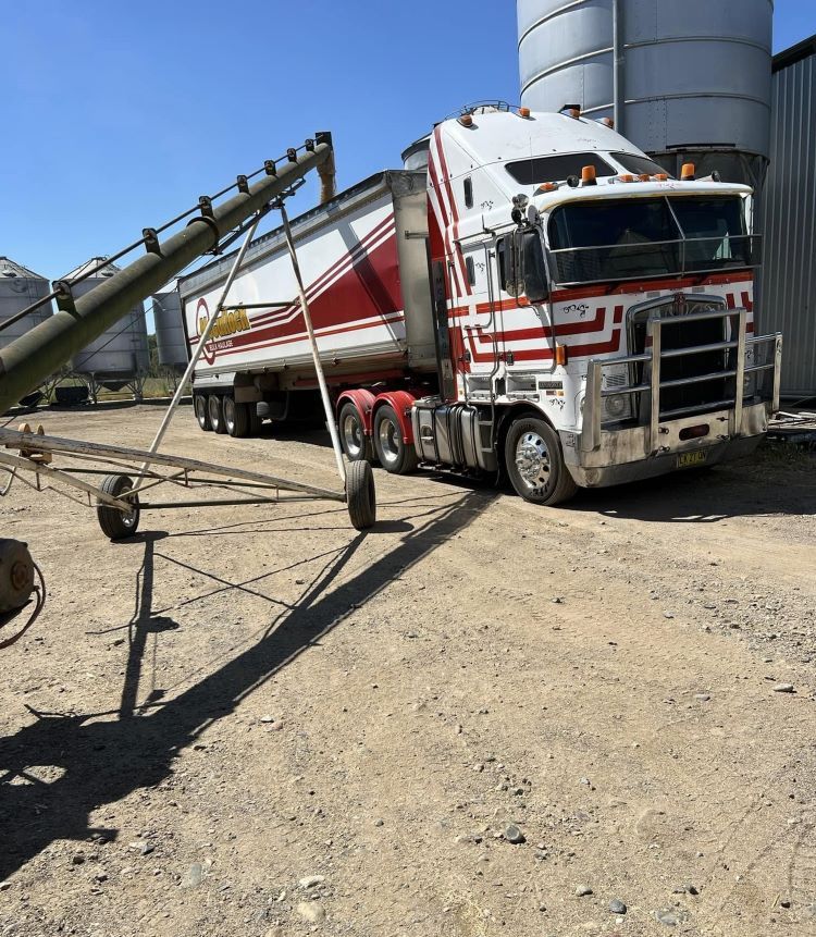 A Red and White Semi Truck is Parked in a Dirt Lot — Grain & Produce In Wallamore, NSW