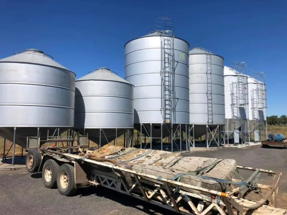 A Trailer is Parked in Front of a Row of Silos — Wallamore Grain & Produce In Wallamore, NSW