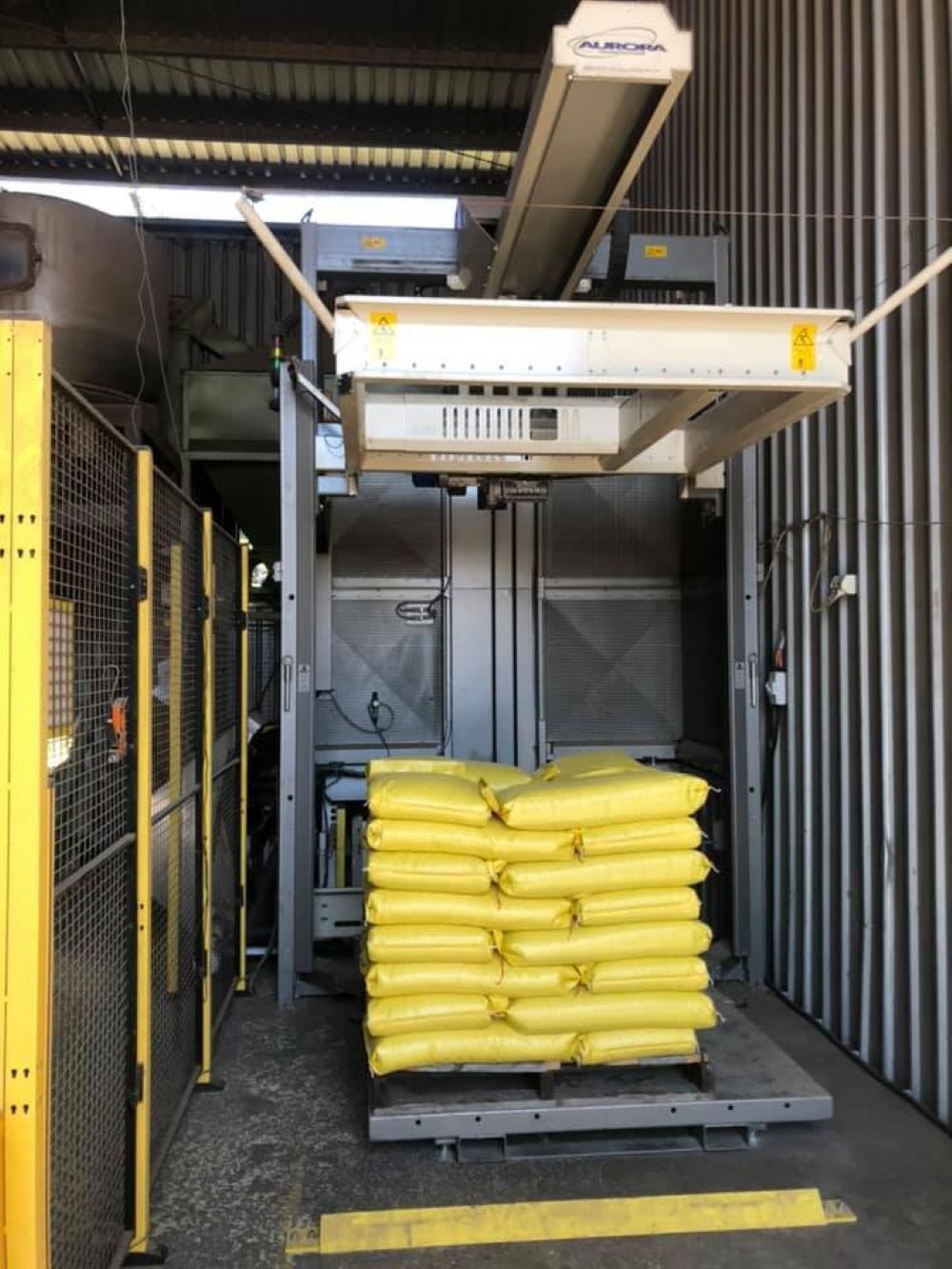 A Machine is Stacking Yellow Bags on a Pallet — Wallamore Grain & Produce In Wallamore, NSW