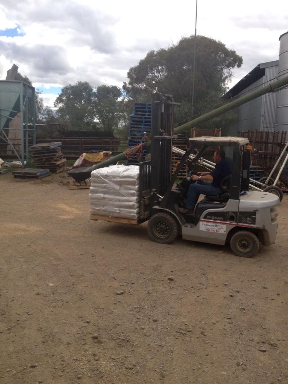 A Man is Driving a Forklift Carrying a Pallet of Bags — Wallamore Grain & Produce In Wallamore, NSW