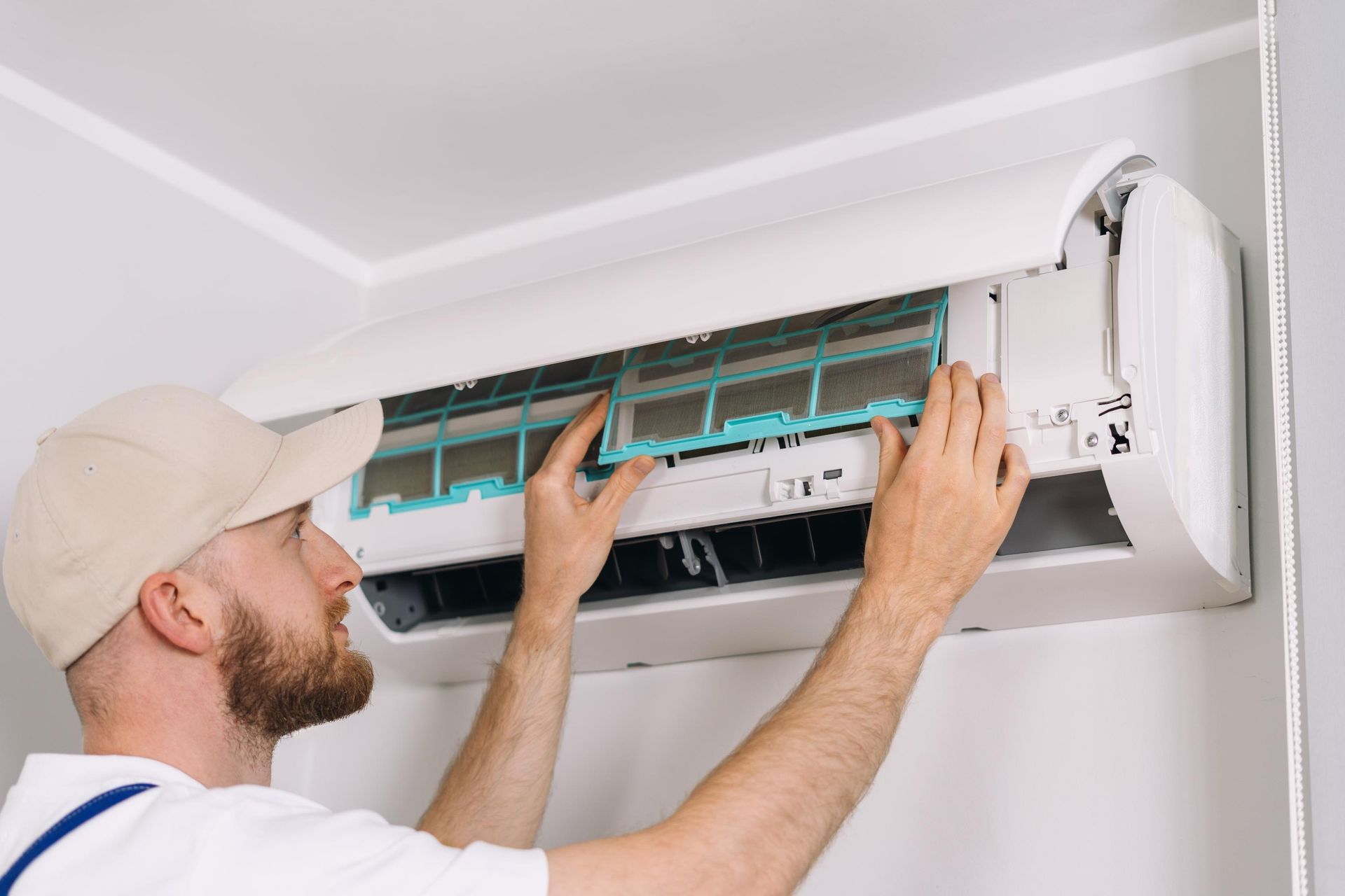 Technician cleaning wall-mounted air conditioner filter indoors