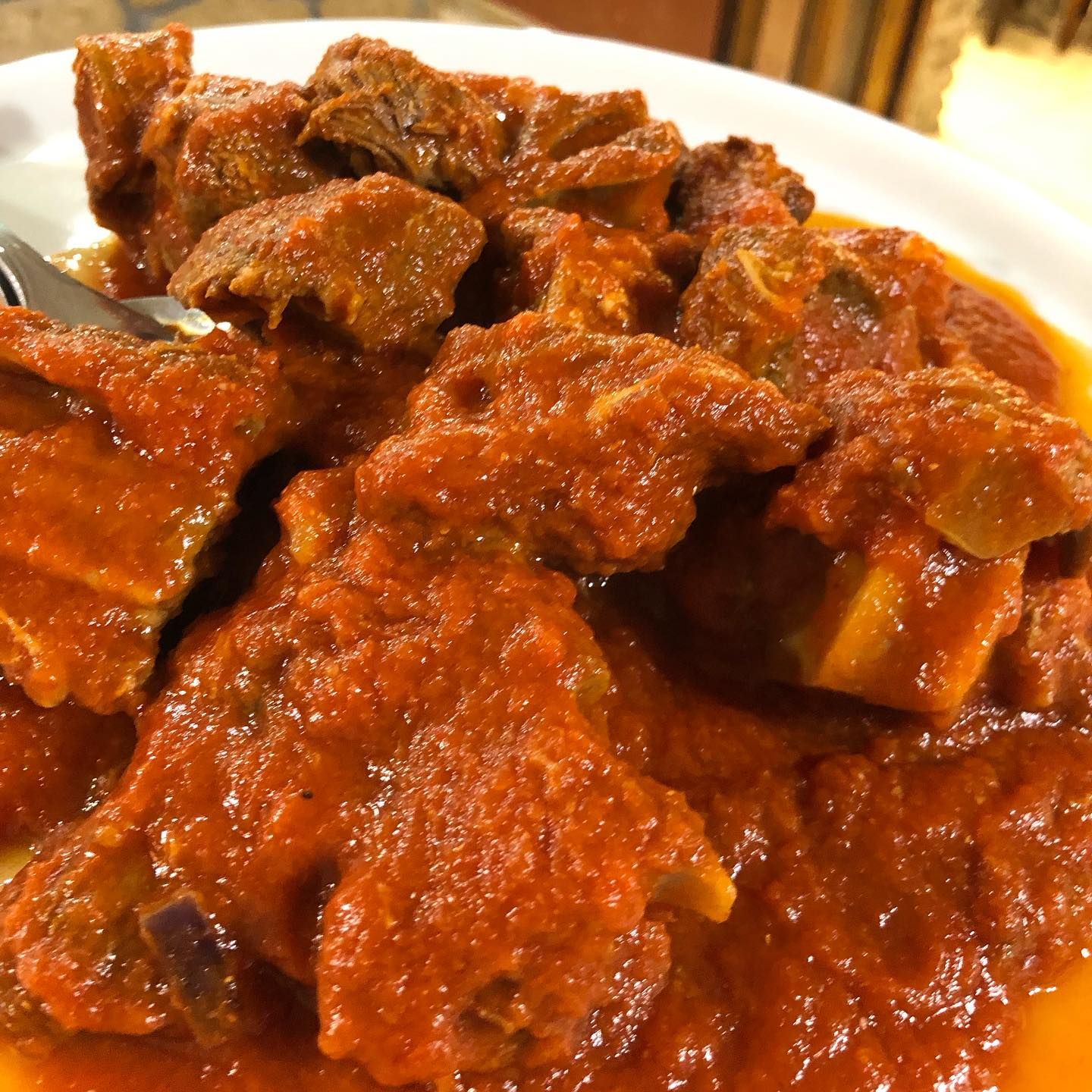 Un piatto di teneri bocconcini di carne generosamente ricoperti da una ricca e densa salsa a base di pomodoro rosso.