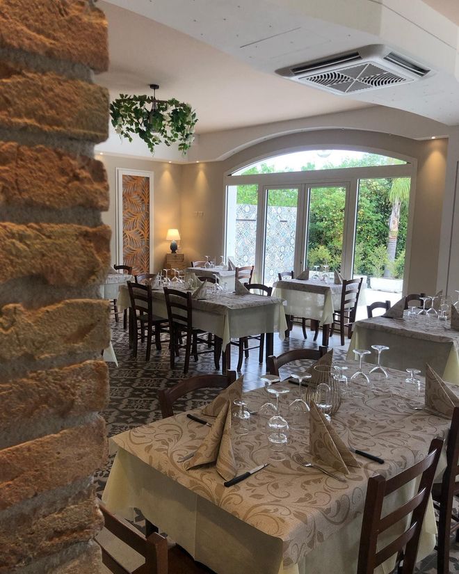 Sala interna elegante e luminosa con tavoli apparecchiati per ospiti e famiglie.