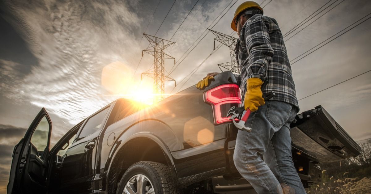 A person wearing yellow gloves and a yellow hard hat holding a hammer.