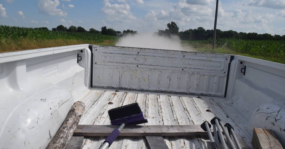 A white pickup truck transporting tools and supplies. The truck bed is covered in scratches and stains.