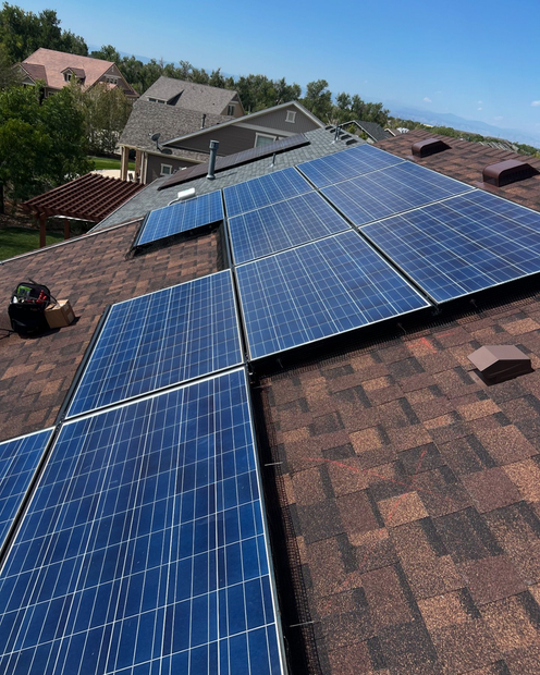 Person in safety gear installing solar panels on a rooftop.