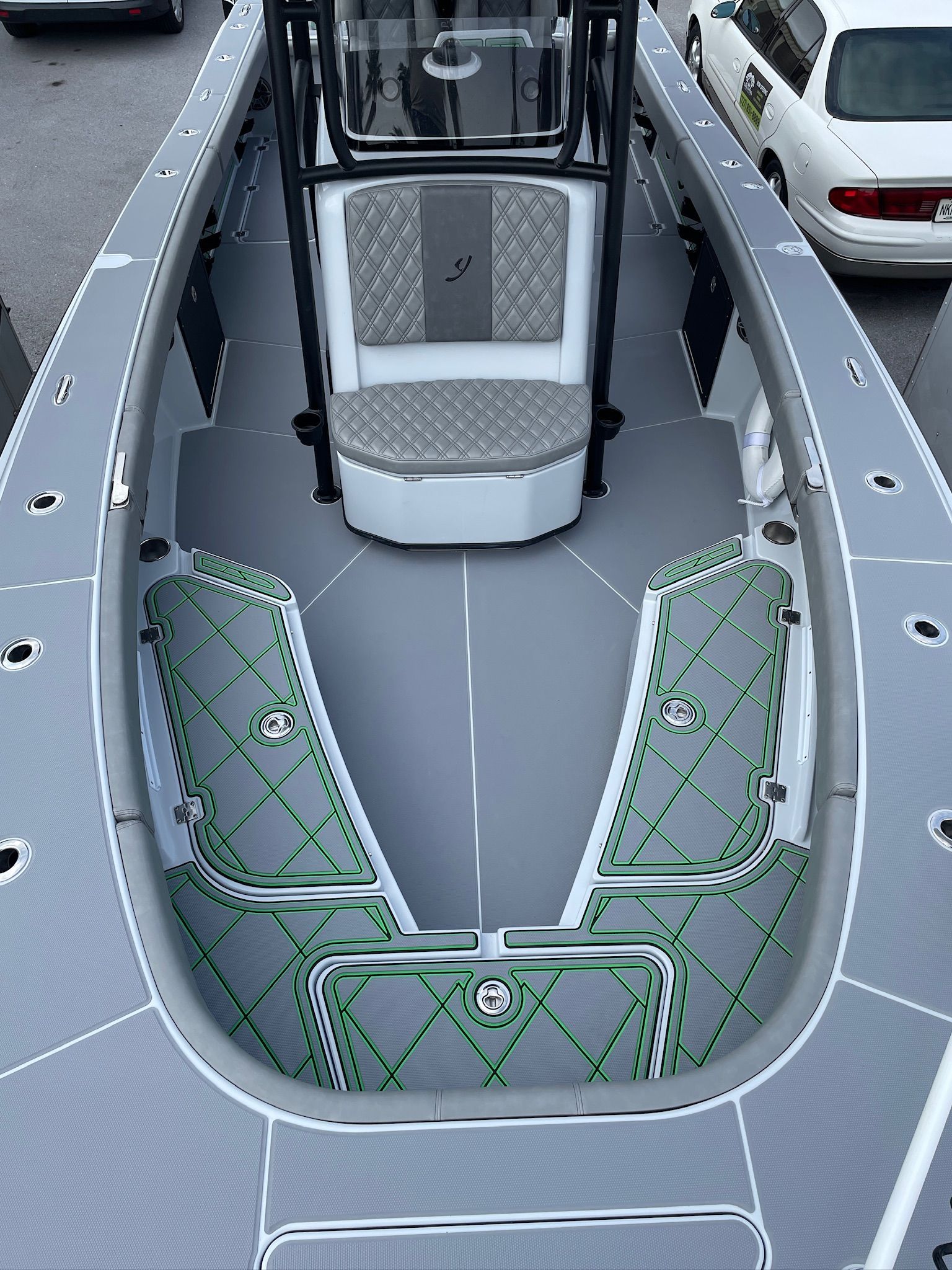 Overhead view of a gray boat with light gray diamond pattern flooring and a white and gray chair, with green accents.