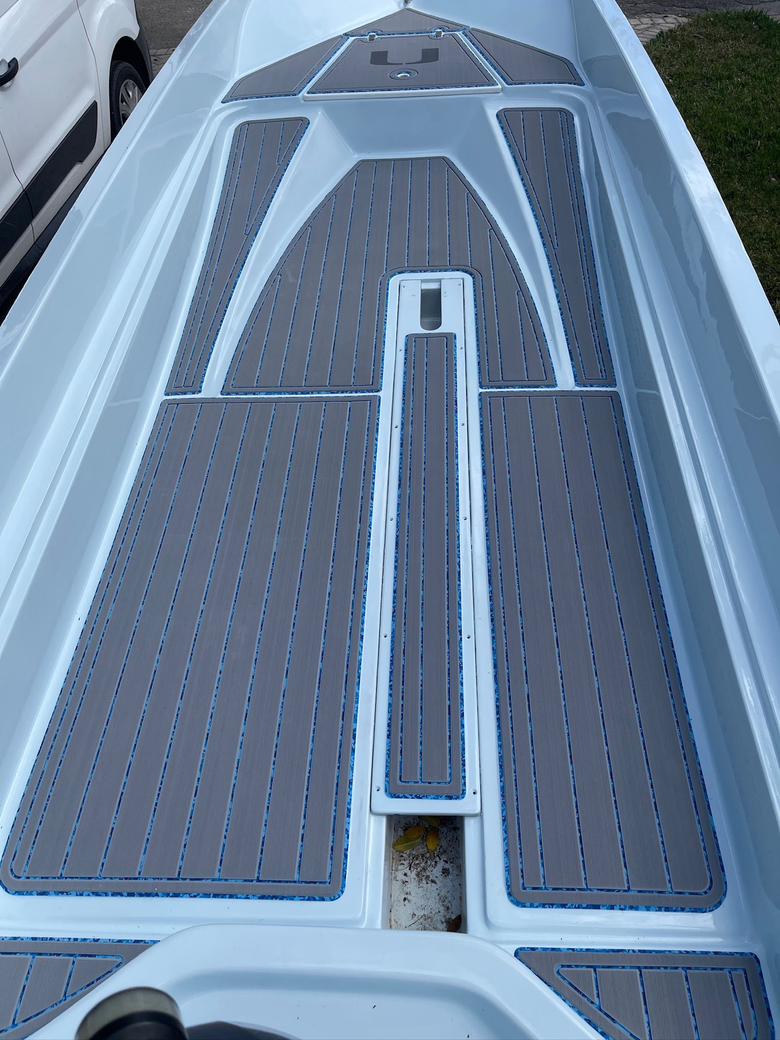 Interior of a boat with gray and blue patterned flooring. White boat sides and trim.