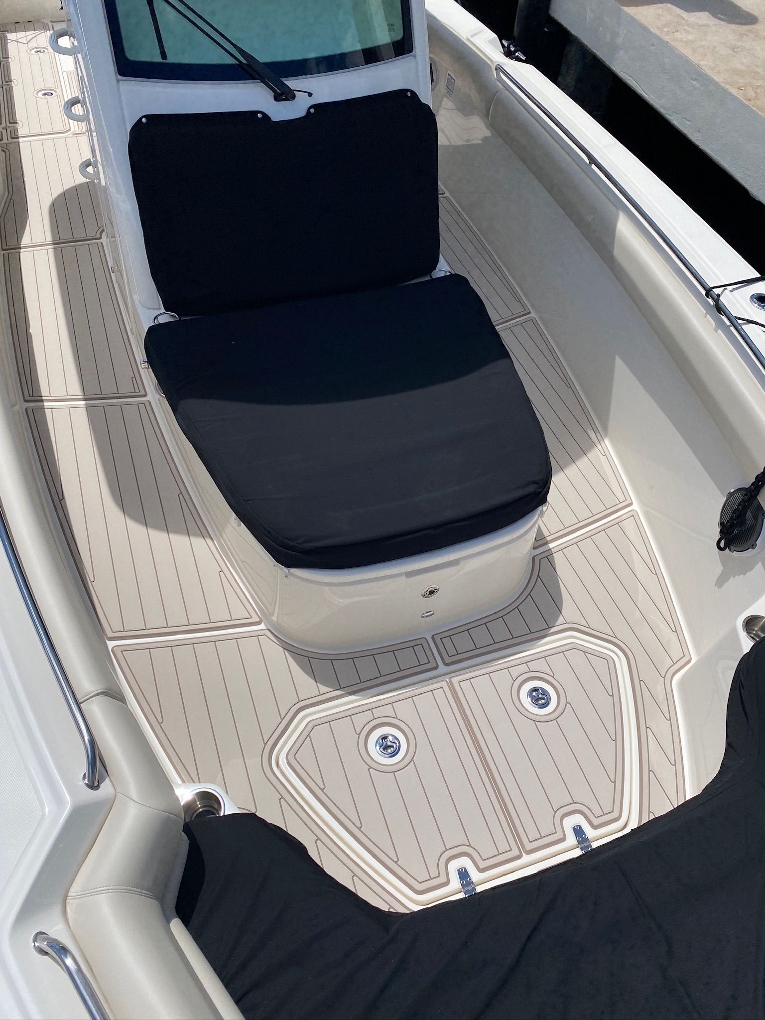 Tan boat deck with black seat cushions.