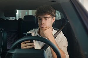 sad man looking at his phone in his car